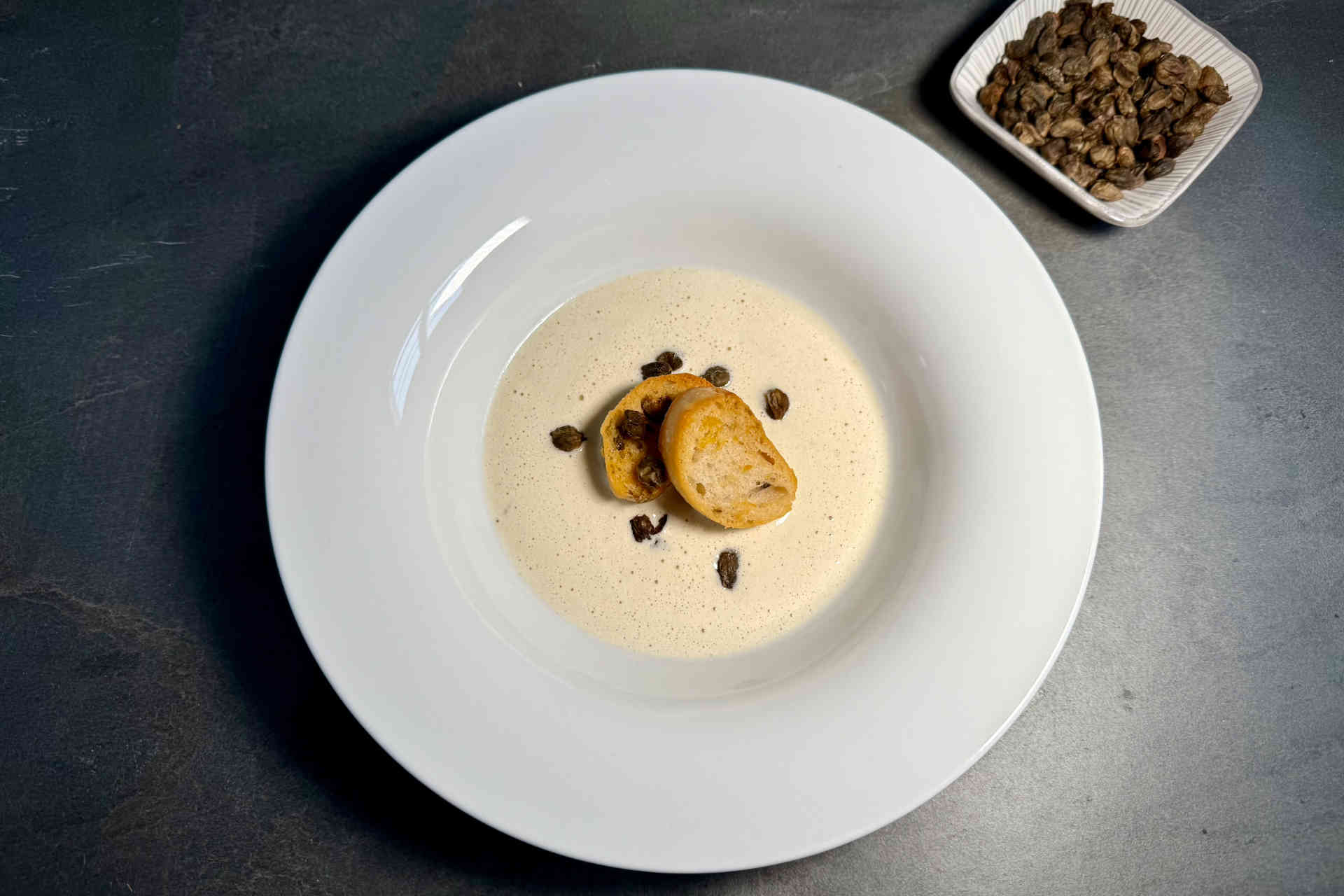 Cremige Montasio-Käsesuppe mit knusprigen Croutons und frittierten Kapern